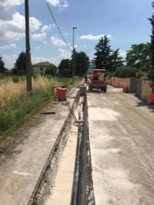 Scavo stradale con tubature e macchinari in lavorazione.