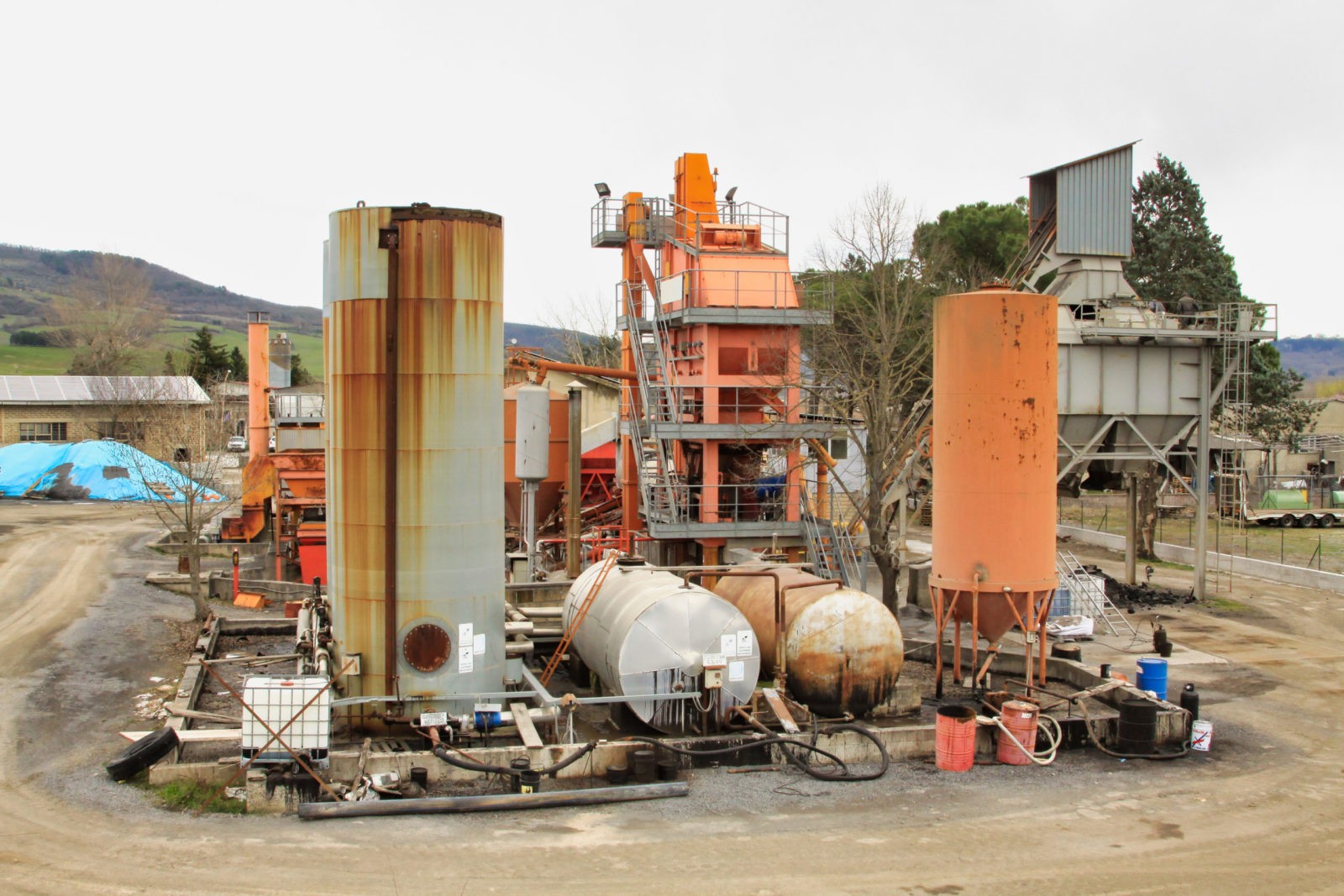 Impianto industriale con serbatoi arrugginiti all'aperto.