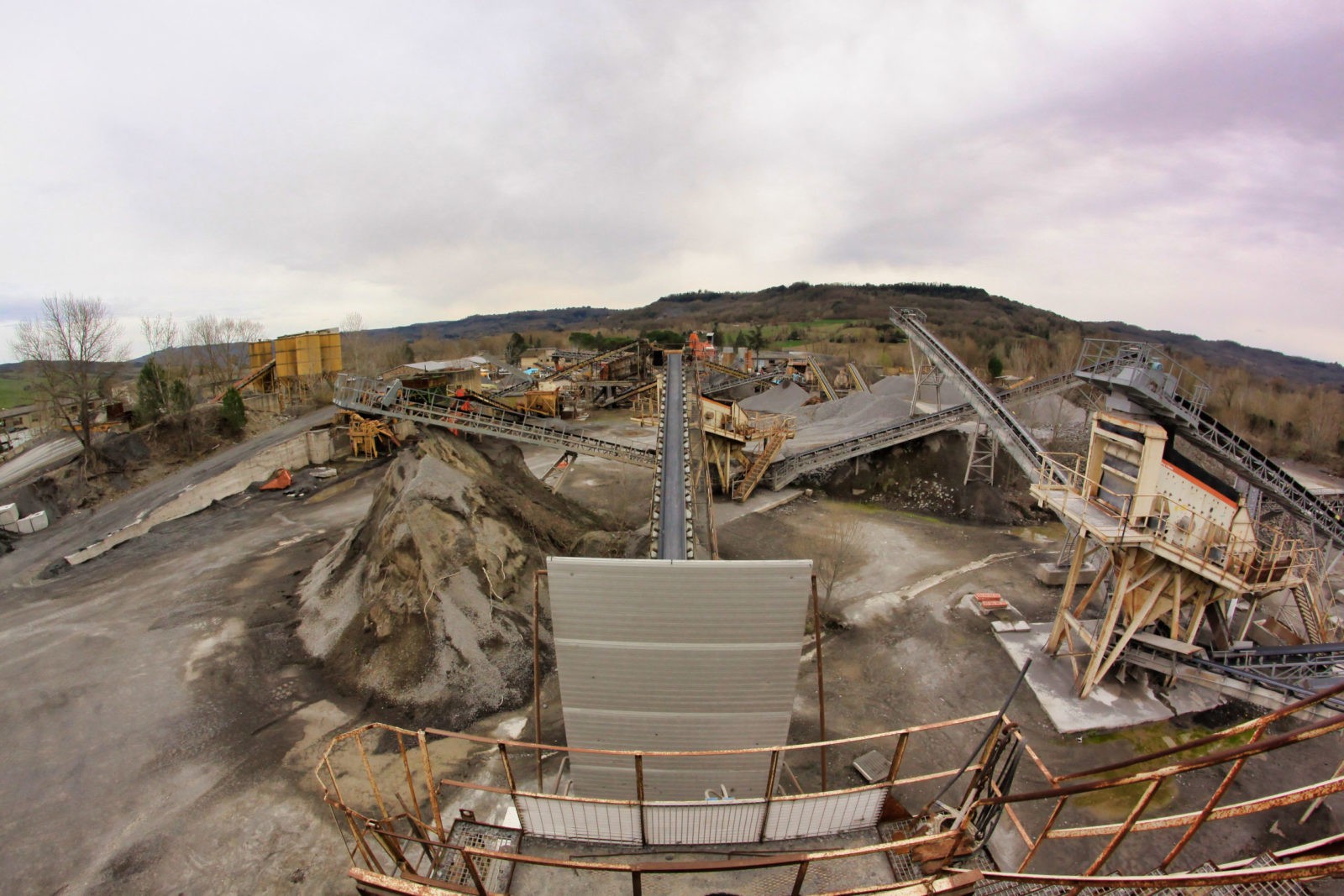 Impianto industriale con nastri trasportatori e cumuli di materiale.