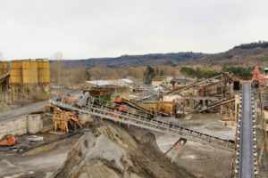 Impianto industriale con nastri trasportatori e strutture metalliche.