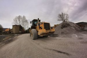 Ruspa gialla vicino a cumulo di terra grigia.