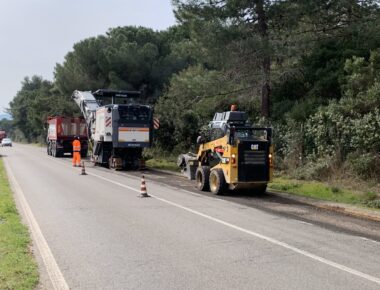 Lavori stradali con macchinari e operai in tuta arancione.