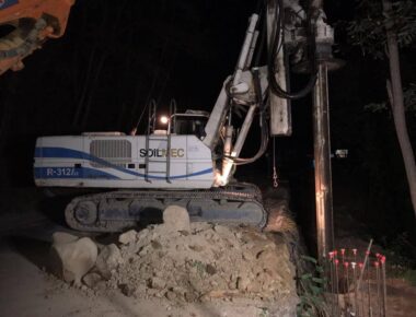 Escavatore al lavoro di notte su terreno roccioso.