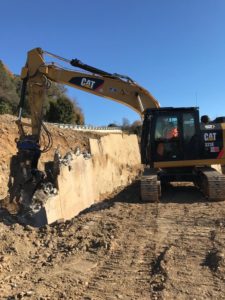 Escavatore giallo in azione su terreno sterrato.