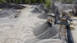 Cava con cumuli di ghiaia e macchinari industriali.