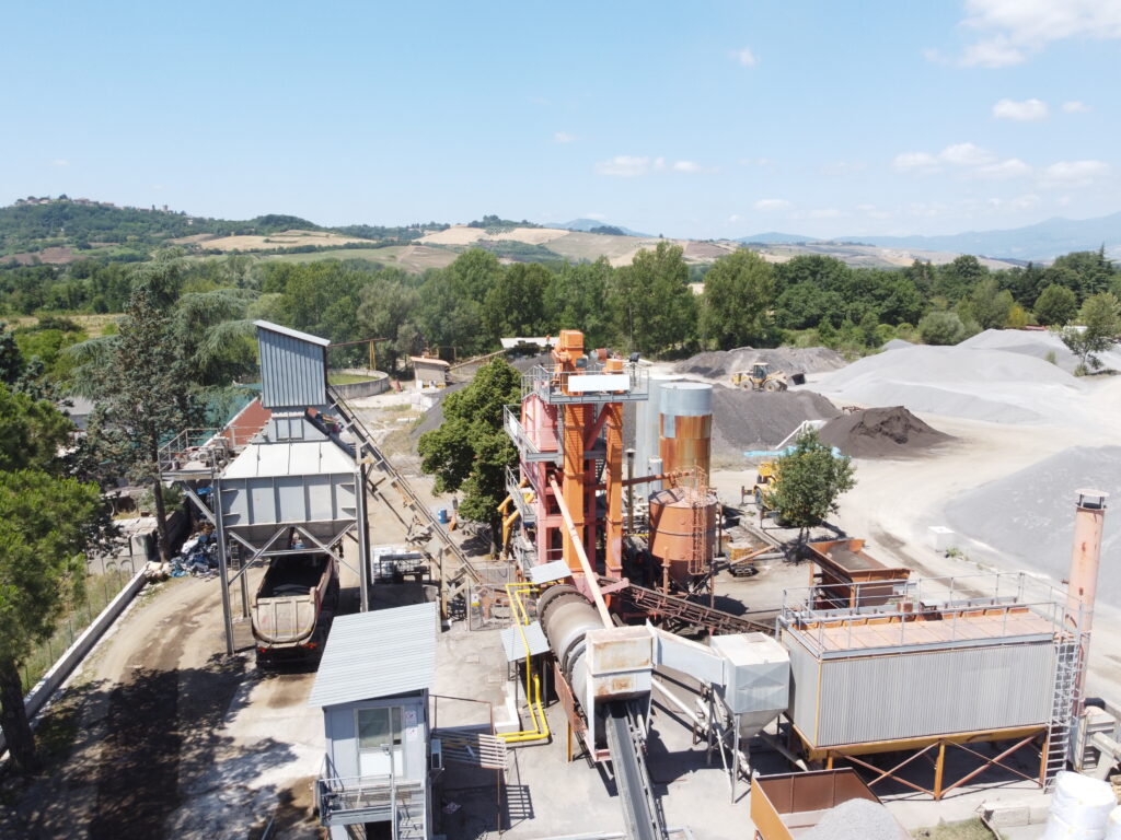 Impianto industriale con macchinari e cumuli di materiali.