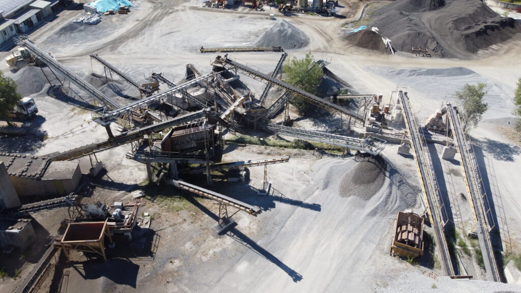 Impianto industriale con nastri trasportatori e cumuli di materiale.