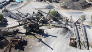 Impianto industriale con nastri trasportatori e cumuli di materiale.