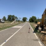Escavatore e camion su strada in costruzione.