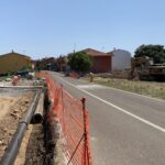 Lavori stradali con escavatore e operai su strada.