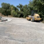 Rullo compressore su strada in costruzione vicino a bosco.