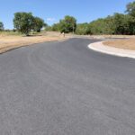 Strada asfaltata curva con alberi sullo sfondo.