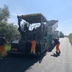 Operai asfaltano una strada con una macchina stenditrice.