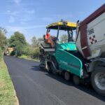 Macchina asfaltatrice lavora su strada appena asfaltata.