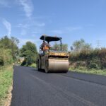 Rullo compressore asfalta strada in ambiente rurale.