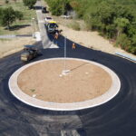 Rotonda stradale in costruzione con operai e macchinari.