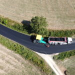 Macchine asfaltatrici lavorano su una strada di campagna.