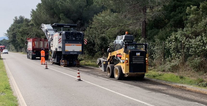 Lavori stradali con macchinari e operai in tuta arancione.