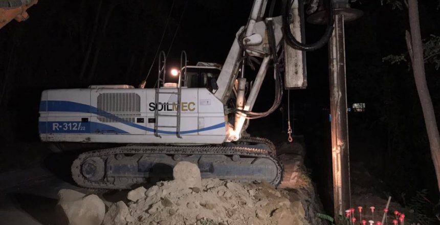 Escavatore al lavoro di notte su terreno roccioso.